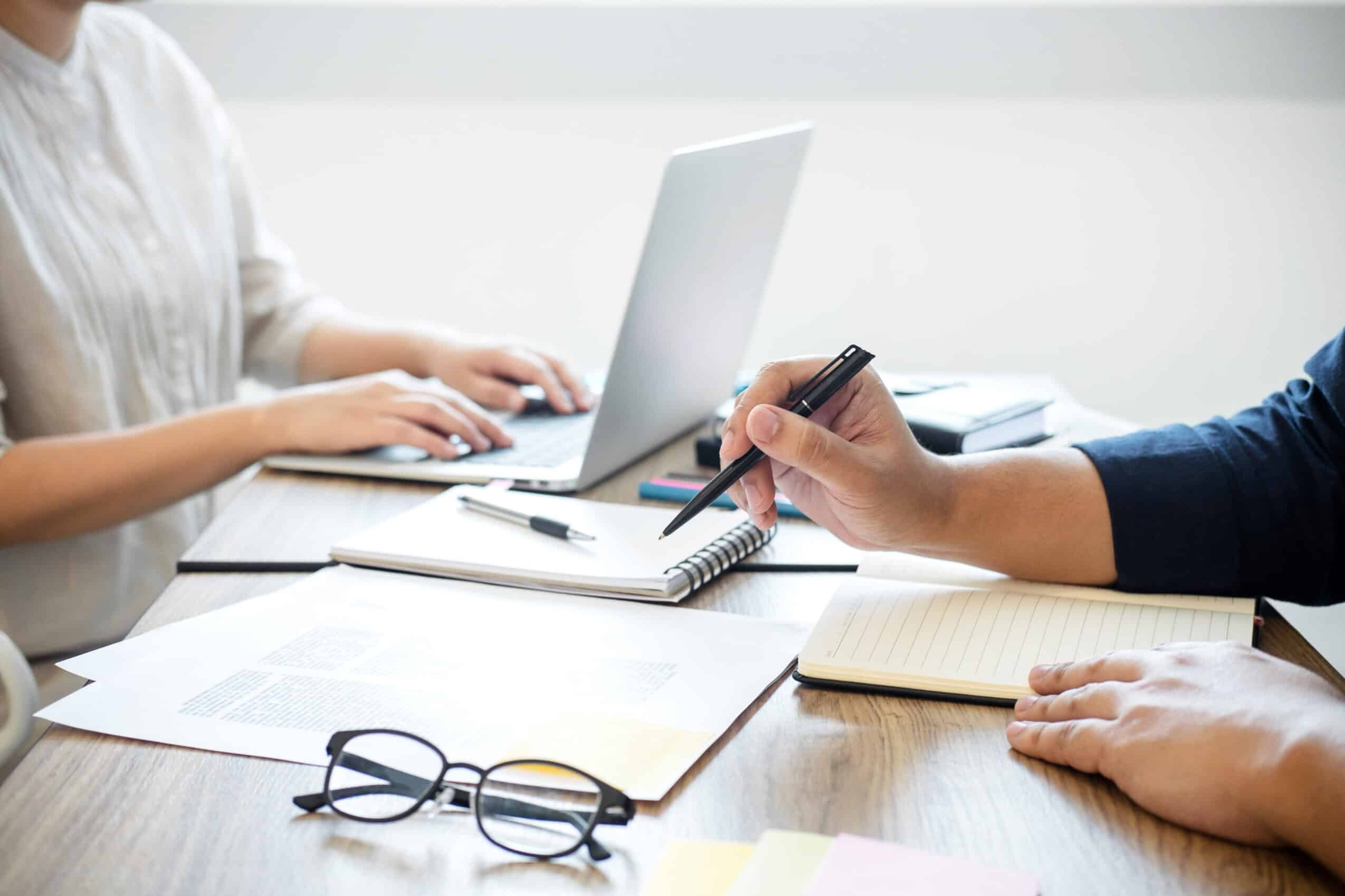 Two people sitting at a desk working on financial documents