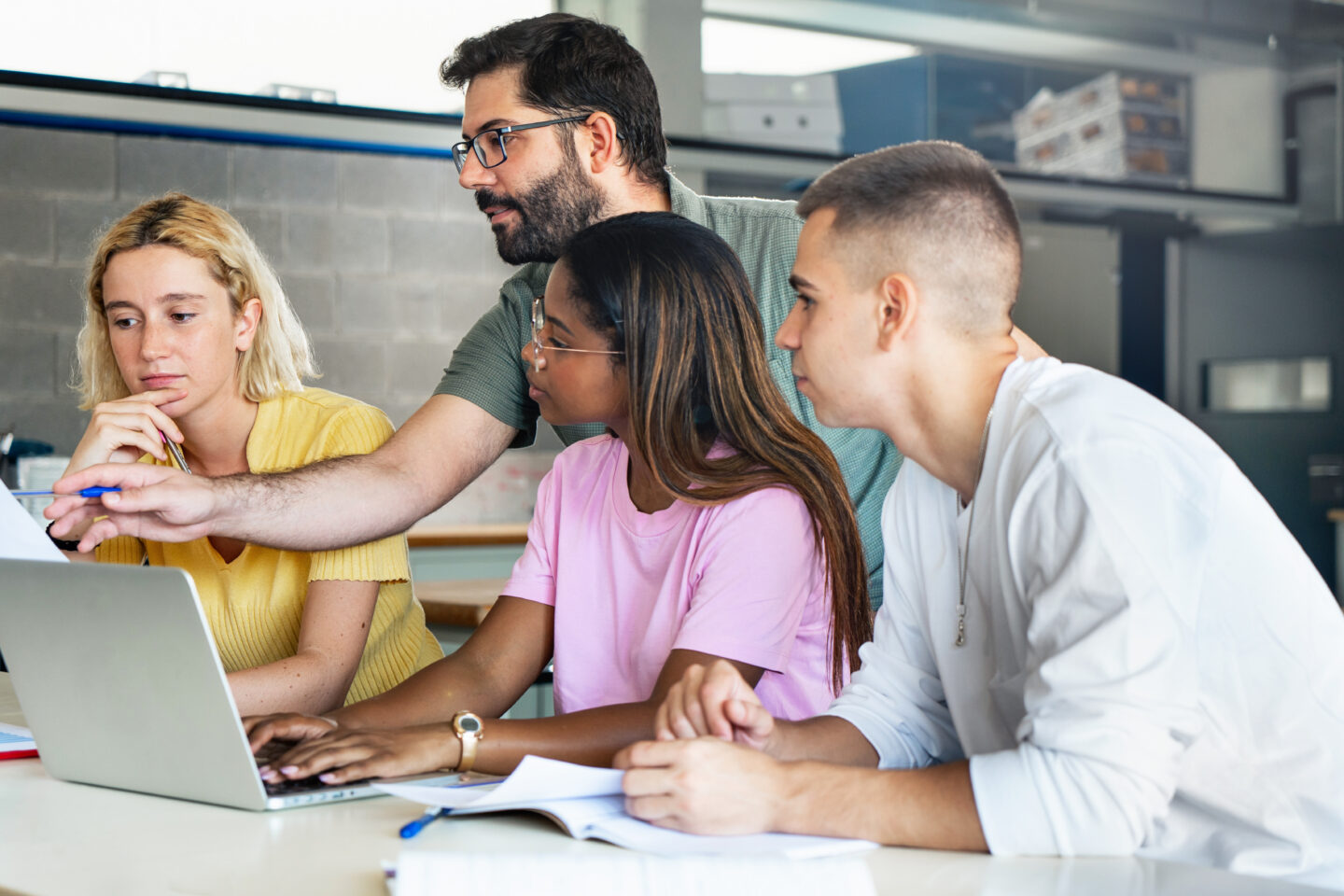 Young teacher helping teenager students at college