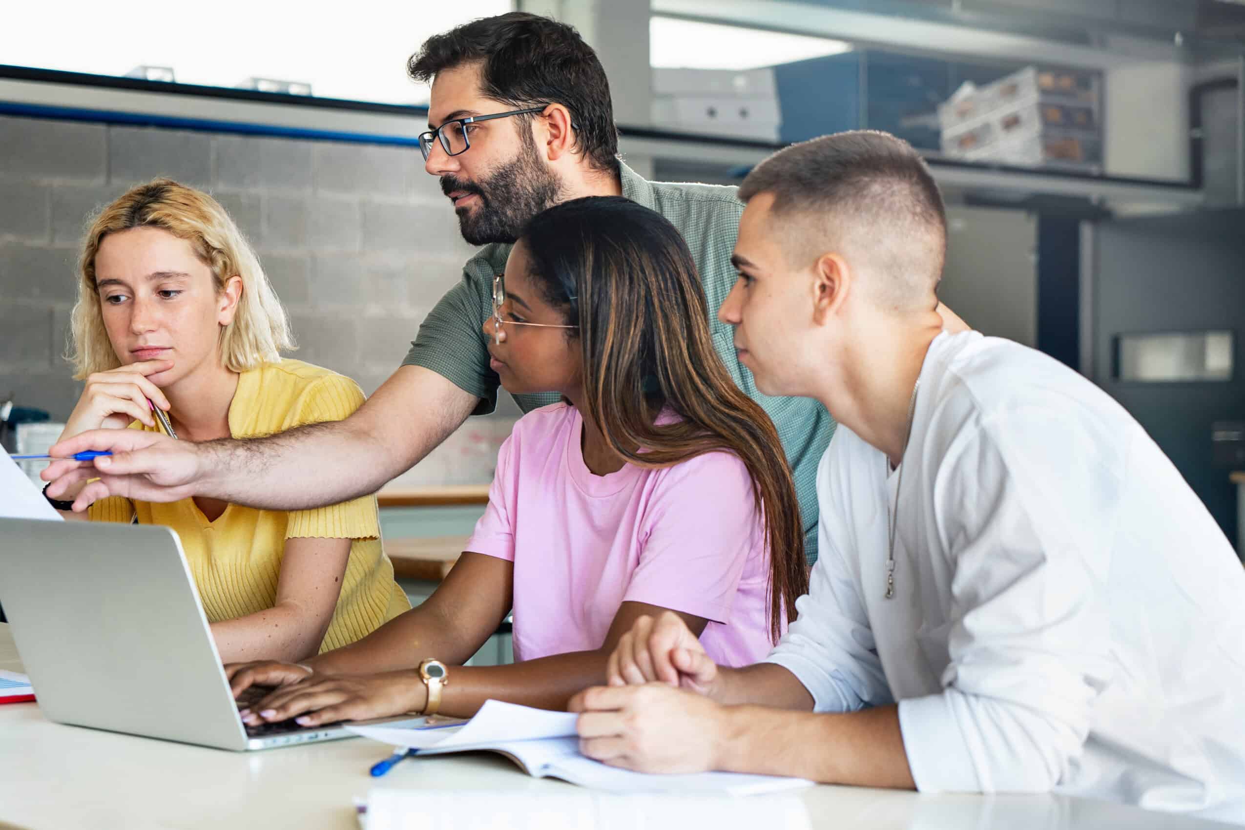 Young teacher helping teenager students at college