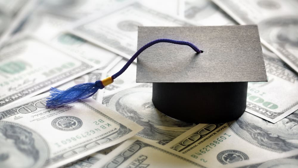 Graduation cap on top of one hundred dollar bills