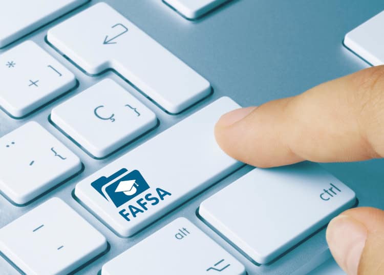 A keyboard with a key changed to the logo of FASFA with a finger pressing down.