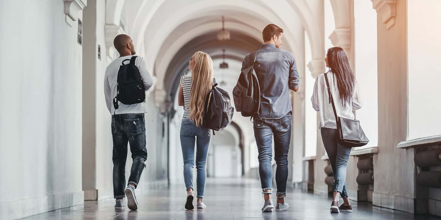 Group of diverse students walking in university corridor, discussing Louisiana college financial aid.