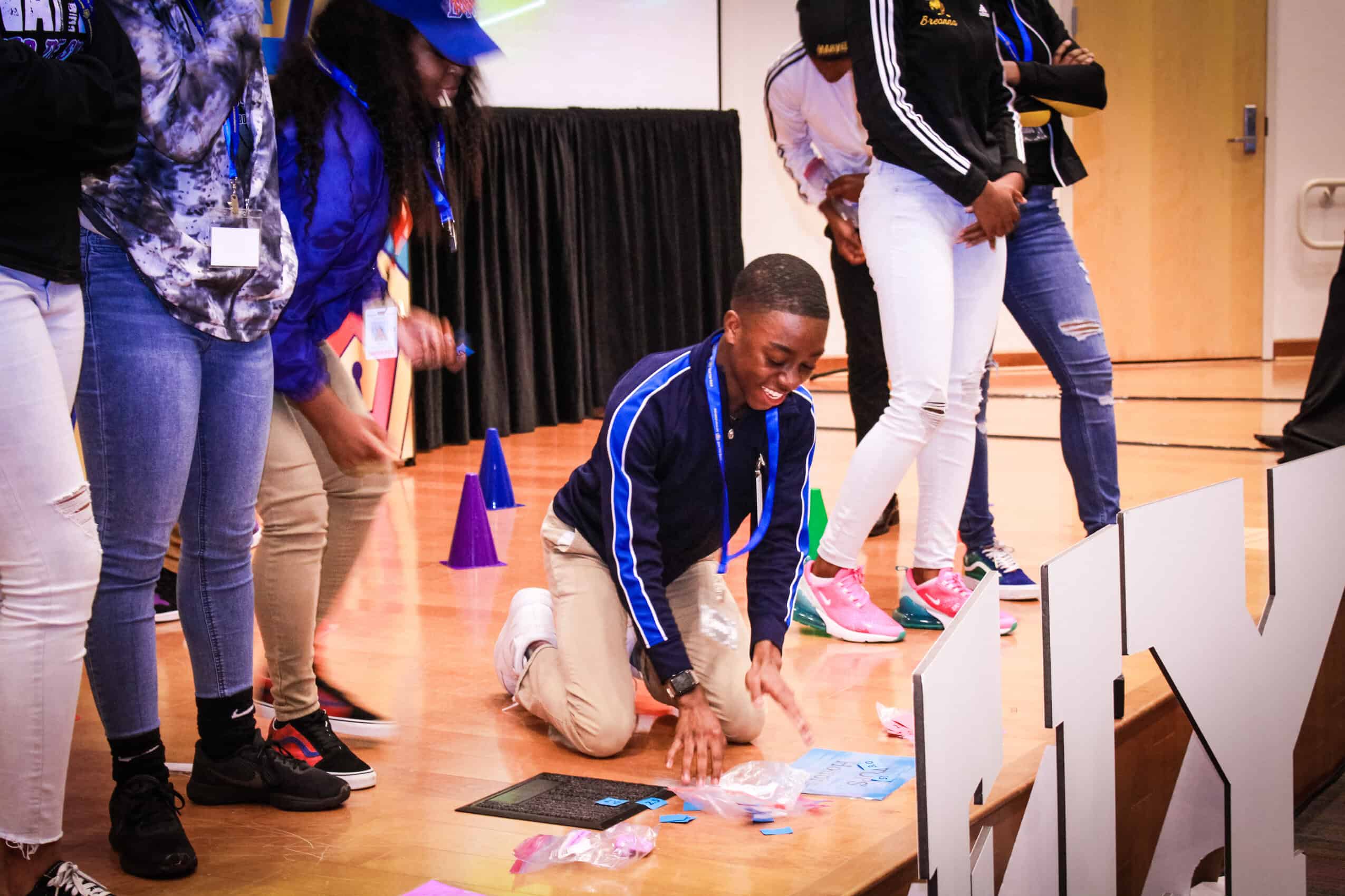 Student kneeling on stage during Louisiana college financial aid event.