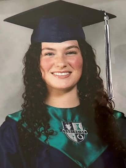 Young woman in cap and gown celebrating Louisiana college financial aid success.