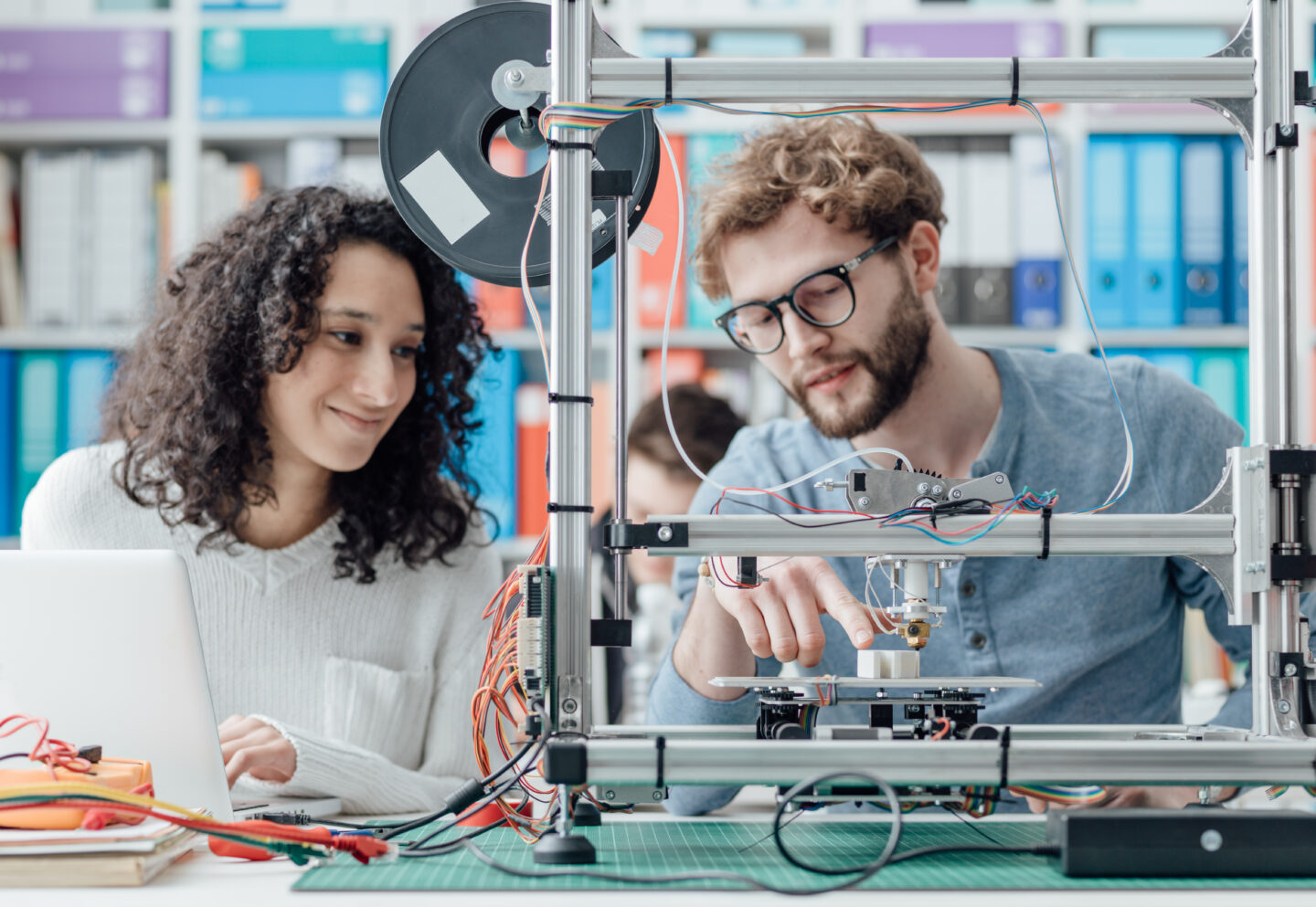 Two students working on a 3D printer for Louisiana college financial aid projects.